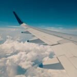 View from airplane window showing wing above clouds representing Ghana's aviation sustainability goals