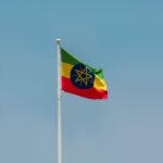 Ethiopian national flag elegantly swaying on a flagpole against a clear blue sky in Addis Ababa.