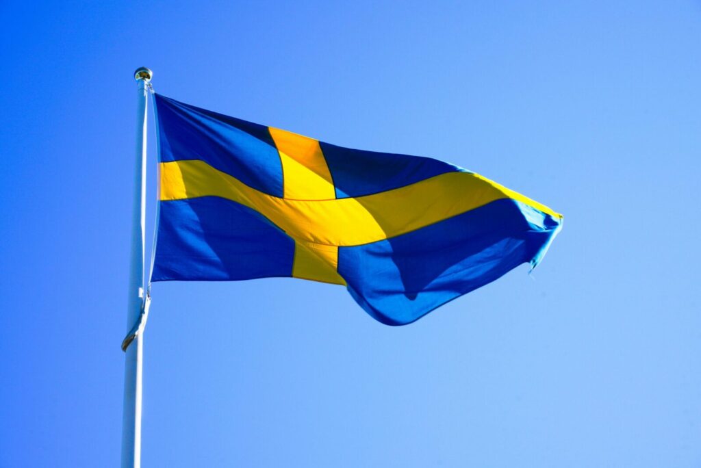 Bright Swedish flag waving on a clear day with blue sky.