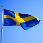 Bright Swedish flag waving on a clear day with blue sky.