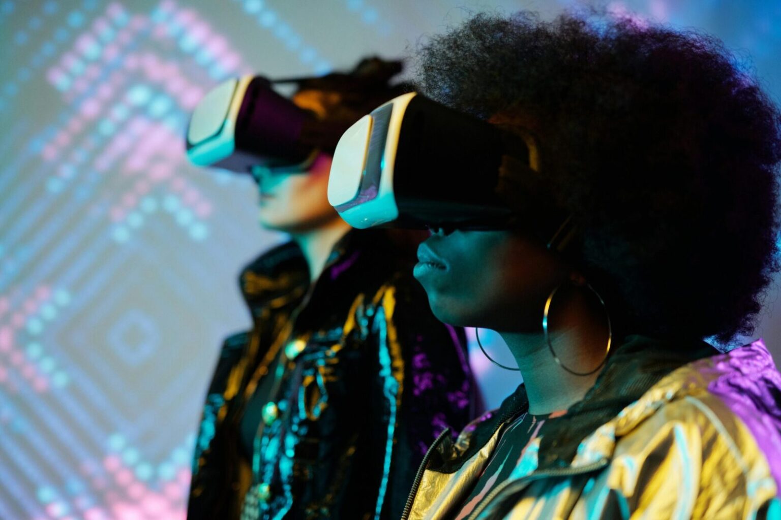 Two women wearing VR headsets immersed in a vivid digital world. Explore technology.
