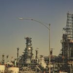 A large industrial refinery with pipes and towers under a clear blue sky during the day.