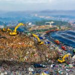 Aerial view showing heavy machinery at a landfill site in West Java, Indonesia.