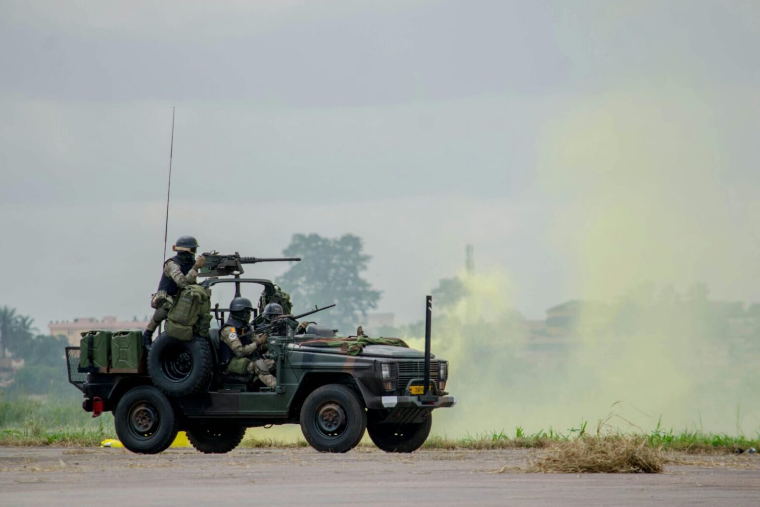Army soldiers operating a military vehicle during a field exercise with smoke effects.