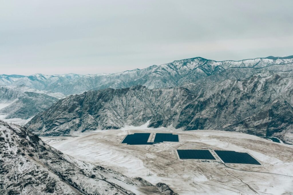 Aerial view of a snow-covered mountain landscape with solar panels.