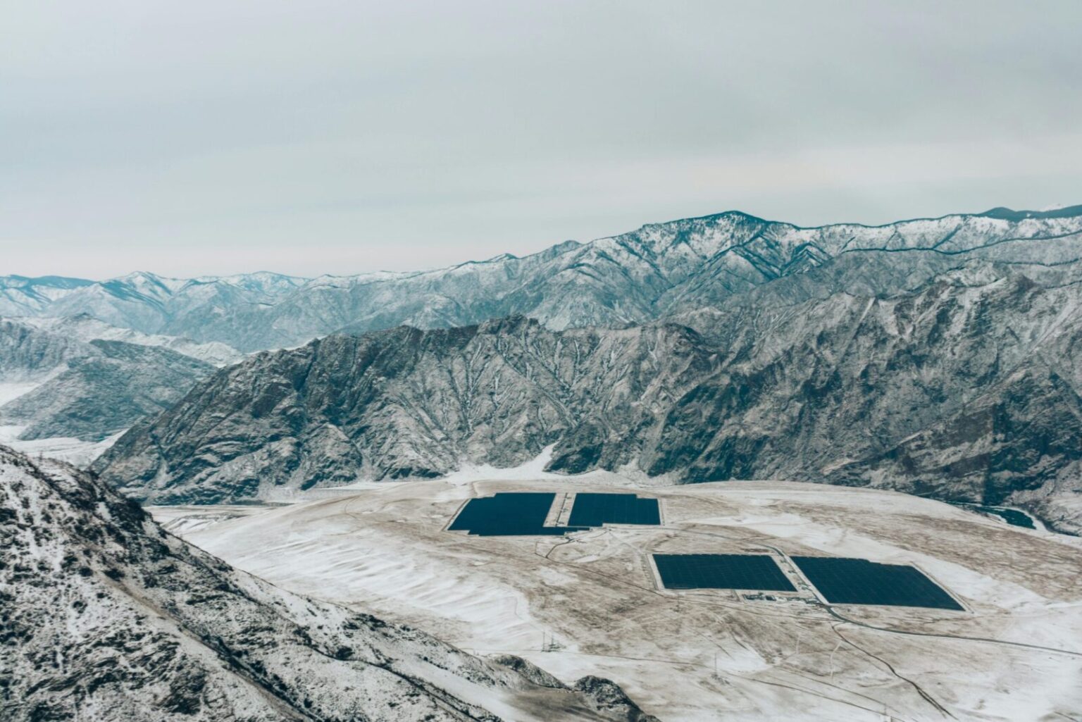 Aerial view of a snow-covered mountain landscape with solar panels.