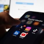 A person holding a smart phone with social media on the screen