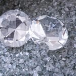 two diamonds sitting on top of a pile of crushed glass