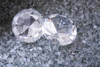 two diamonds sitting on top of a pile of crushed glass