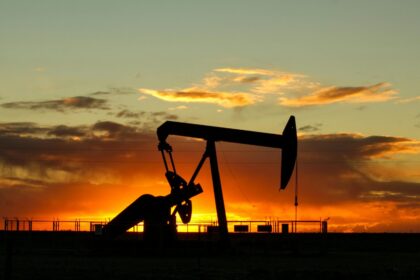 Dramatic silhouette of an oil pump jack against a vibrant sunset sky, emphasizing energy extraction.