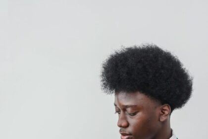 A young black man in a suit using a smartphone against a white background. Studio shot.