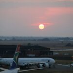 Sunrise over an airport tarmac with parked airplanes.