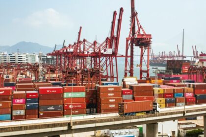 A bustling scene of cargo containers and cranes at a Hong Kong port, showcasing global trade.