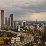 Aerial view of Nairobi's modern skyline and expressway under cloudy skies.