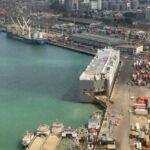 Aerial view of a bustling sea port with cargo ships and containers, highlighting global trade logistics.