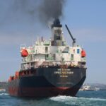 Oil tanker OPEC Victory sailing on the Bosporus under clear skies, emitting smoke.