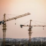 Skyline view of an urban construction site with prominent tower cranes at dusk.