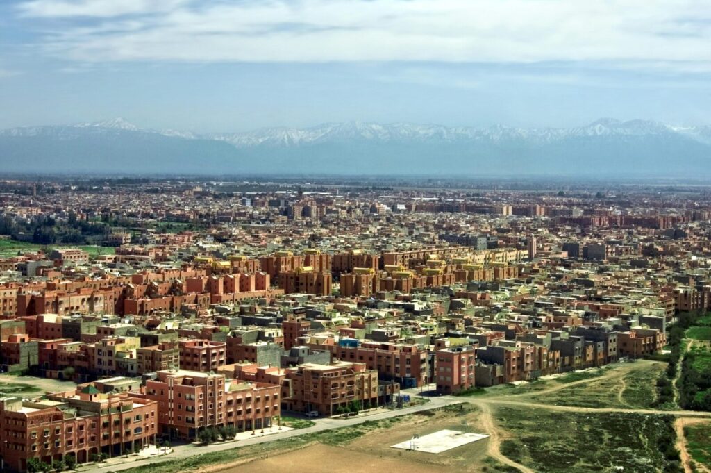 Stunning aerial view of Marrakech cityscape with Atlas Mountains in the background.