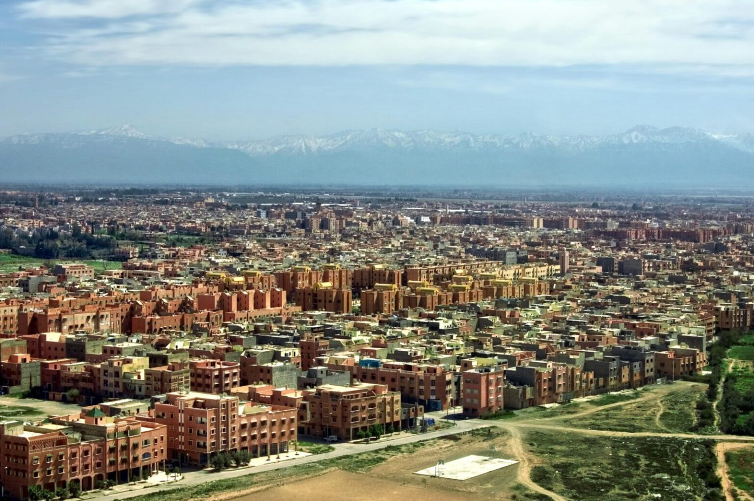 Stunning aerial view of Marrakech cityscape with Atlas Mountains in the background.