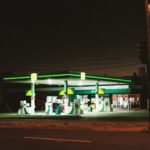 Illuminated BP gas station at night in Melbourne, showcasing urban life.
