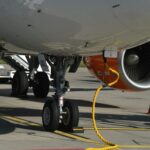 Detailed view of airplane landing gear and engine on tarmac in Geneva, Switzerland.