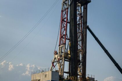 Oil rig in action during sunset, featuring heavy machinery and a lone worker on site.