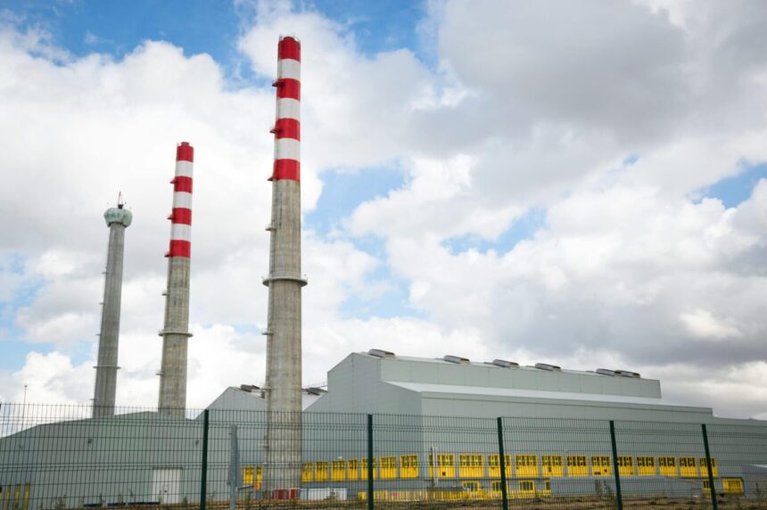 Factory chimneys against a blue sky symbolize industrial power and environmental impact.
