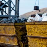 Close-up of rusty mining carts filled with various minerals in an industrial setting.
