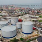 Large industrial tanks sit near a cityscape.