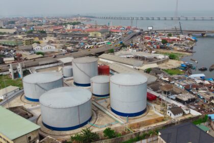 Large industrial tanks sit near a cityscape.