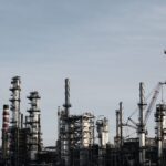 Skyline view of an industrial factory with tall chimneys against a clear sky.