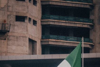 Nigerian flag fluttering against a modern city building backdrop, symbolizing national pride.