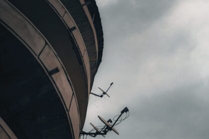 Satellite dishes against a cloudy sky create a moody urban scene.