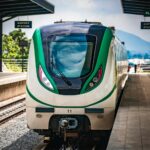 A green and white train pulling into a train station