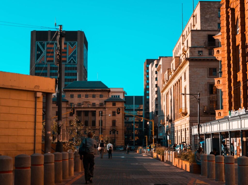 A vibrant city street scene with people walking among urban architecture and buildings.