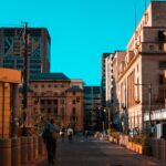 A vibrant city street scene with people walking among urban architecture and buildings.